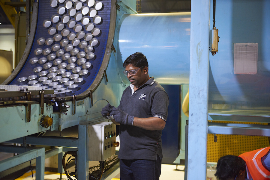 Employee standing in a factory with can manufacturing equipment